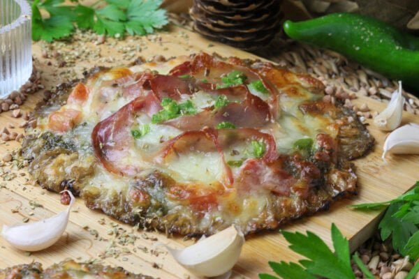 Side view of a parasol mushroom pizza with golden baked mozzarella and prosciutto on top.