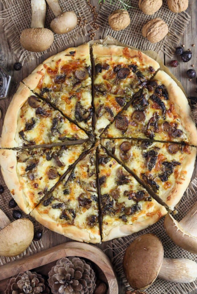 Pizza with porcini mushrooms, served on a wooden table with decoration around.