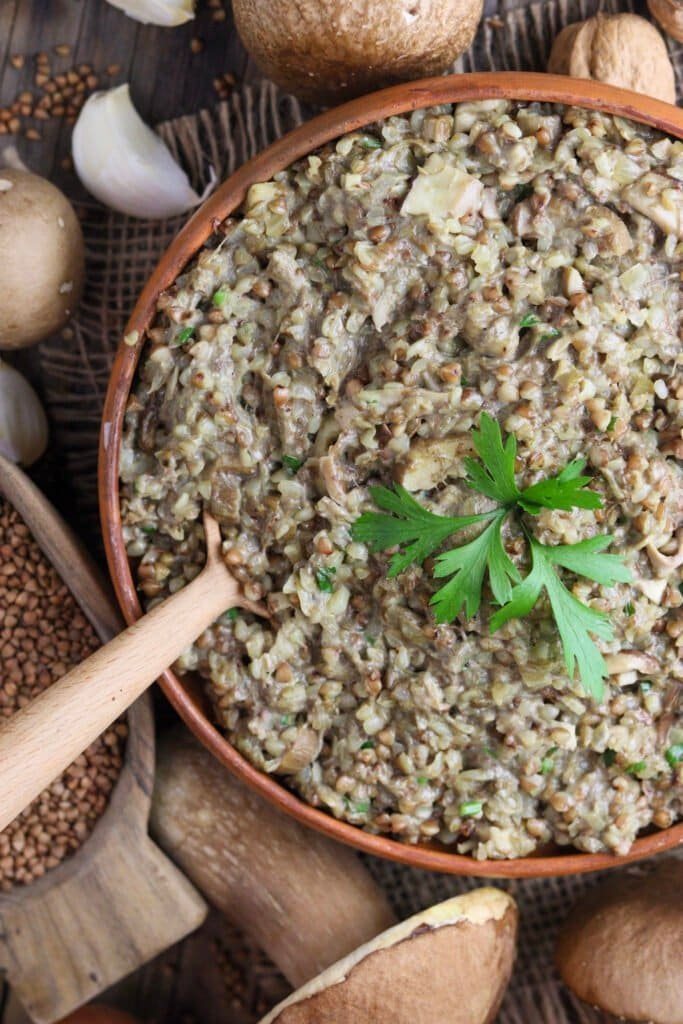 Creamy porcini and buckwheat on a rustic wooden table, served in a clay bowl for a delicious fall dinner.