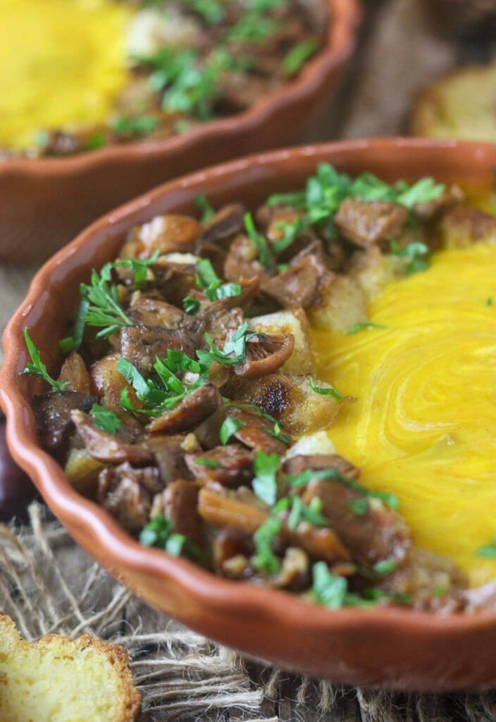 Saffron milk cap mushrooms and bread croutons on top of a bowl of red kuri squash soup.