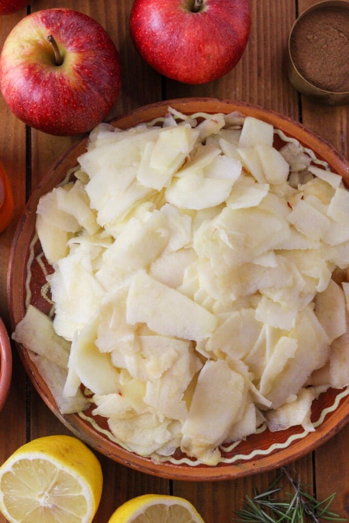 A plate with sliced apples with cinnamon and a lemon cut in half in the background.