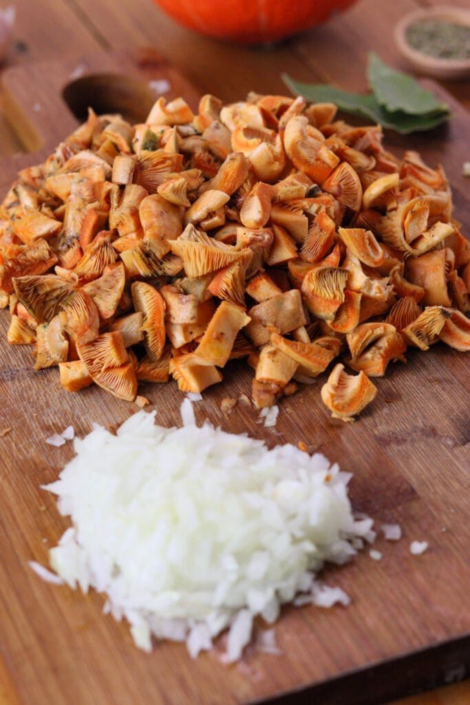 Sliced mushrooms and onions with a red kuri squash in the background.