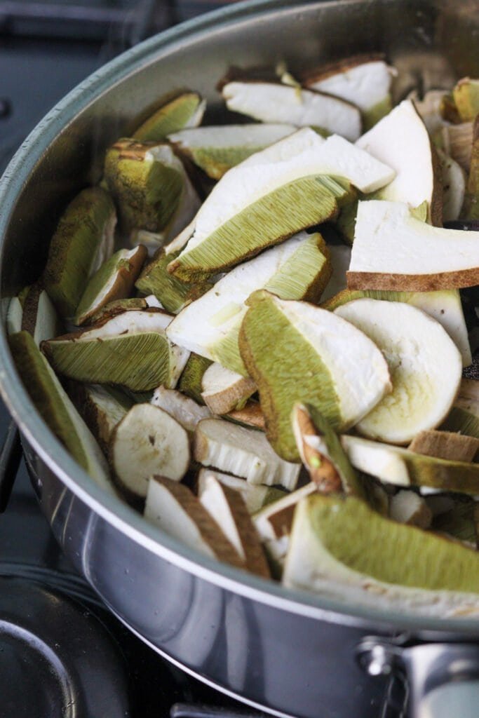 Adding fresh porcini slices to a pan with fried onions.