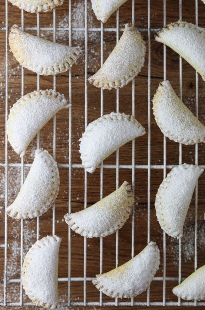 How to sprinkle the empanada cookies with powdered sugar while they cool on a cooling rack