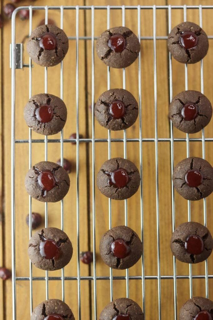 Buckwheat cookies placed on a cooling rack after baked and filled with hot strawberry jam