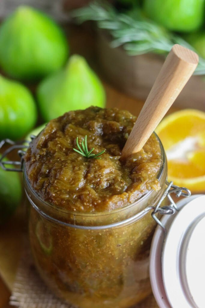 Sugar-free fig jam recipe for canning, packed into a jar with a wooden spoon and fresh figs surounding it