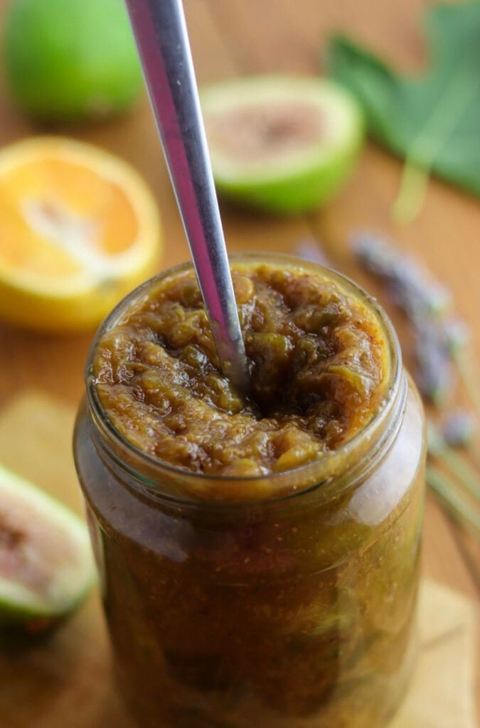 Using a small spoon to press fig jam down in the jar and release air bubbles