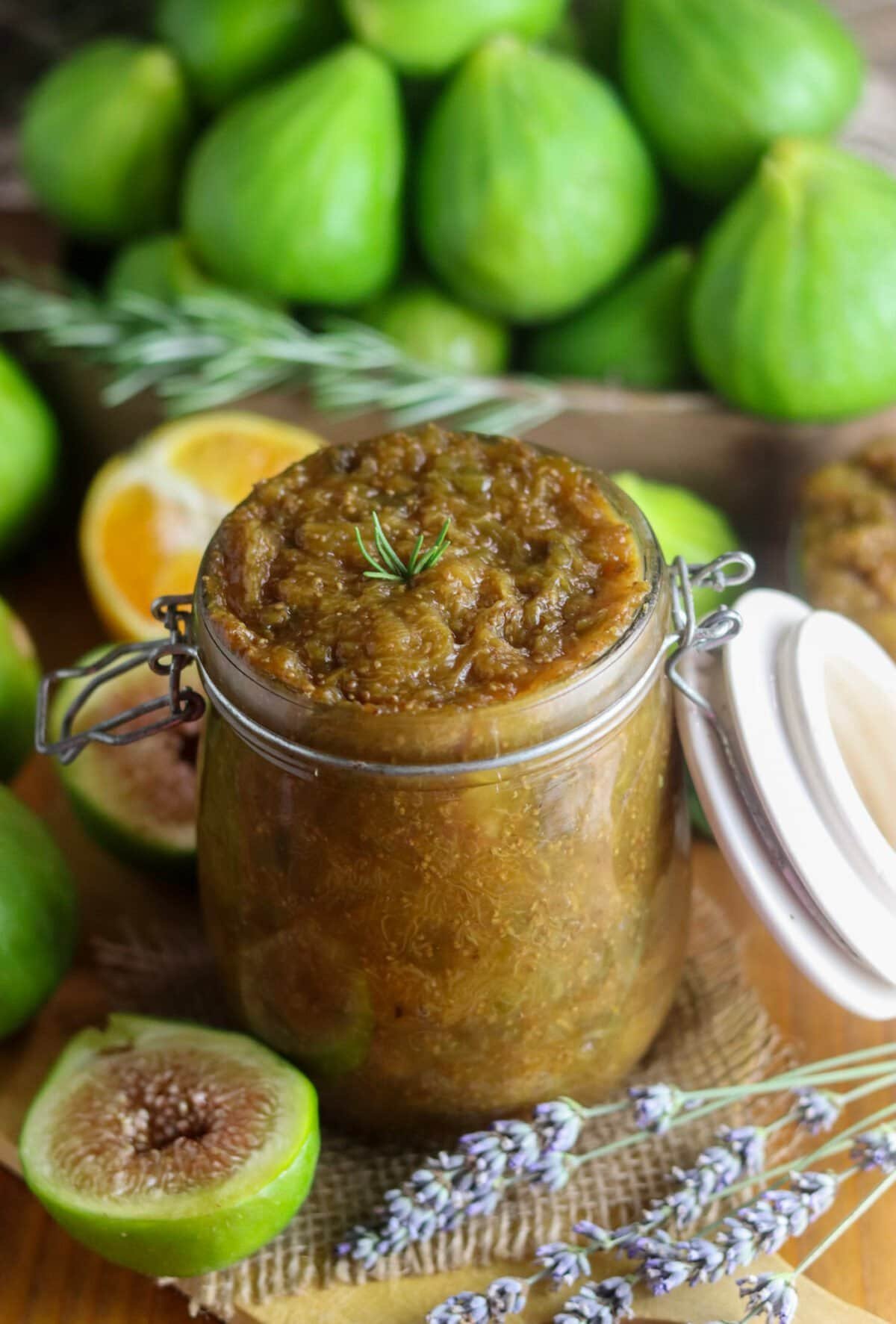 Shelf-stable sugar-free fig jam in a jar, prepped for canning with rosemary and orange zest, fresh figs in the background.