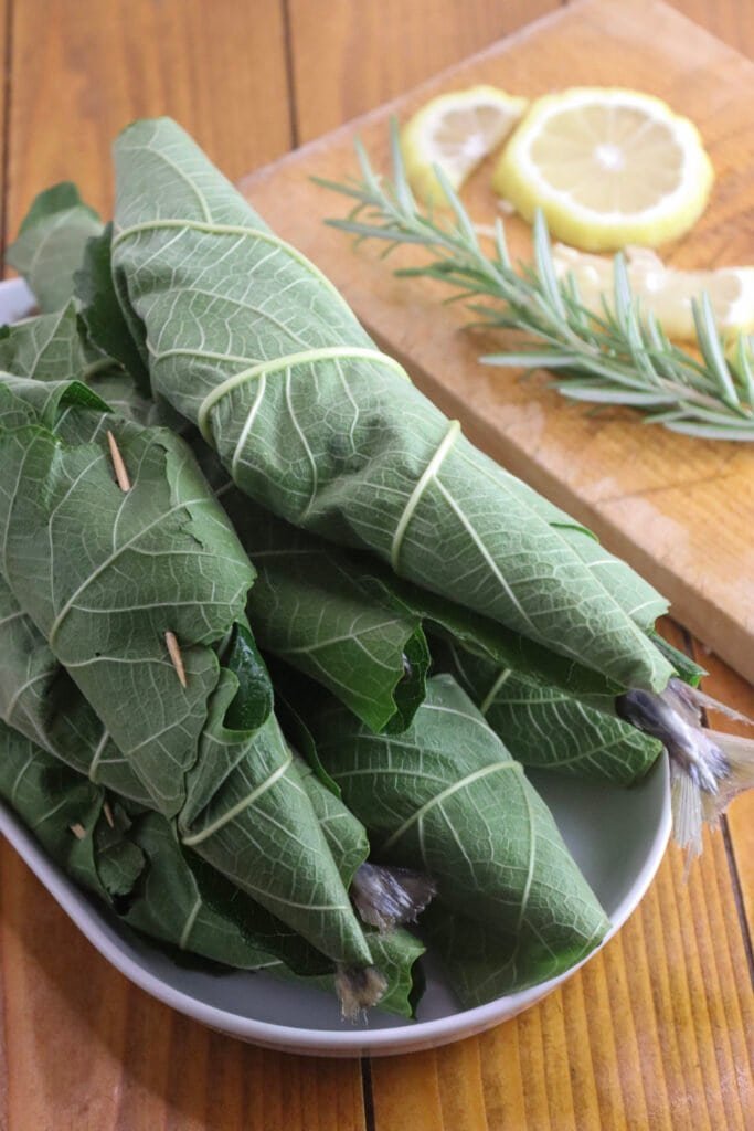 A full plate of wrapped mackerels in fig leaves, closed with a toothpick.