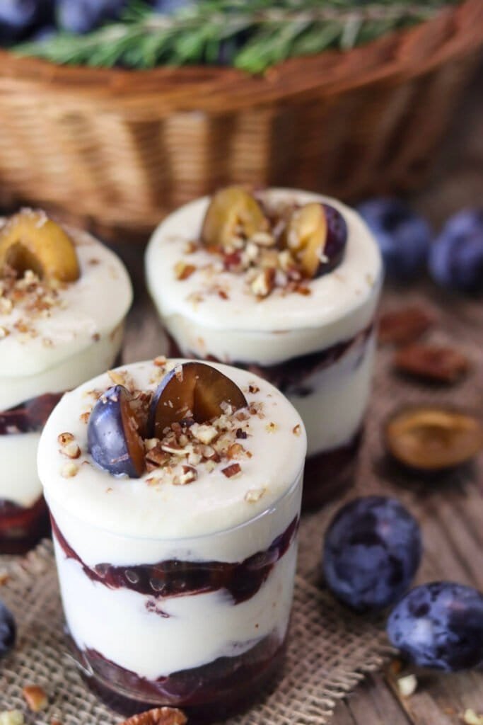 Delicious plum white chocolate parfait jars on a wooden table, just chilled and ready to be eaten.