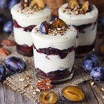 Roasted plum parfait with white chocolate on a wooden rustic table.